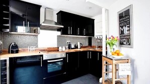 Eine moderne Küche mit schwarzen Schränken, einer Holz Arbeitsplatte und einer Edelstahl-Dunstabzugshaube.