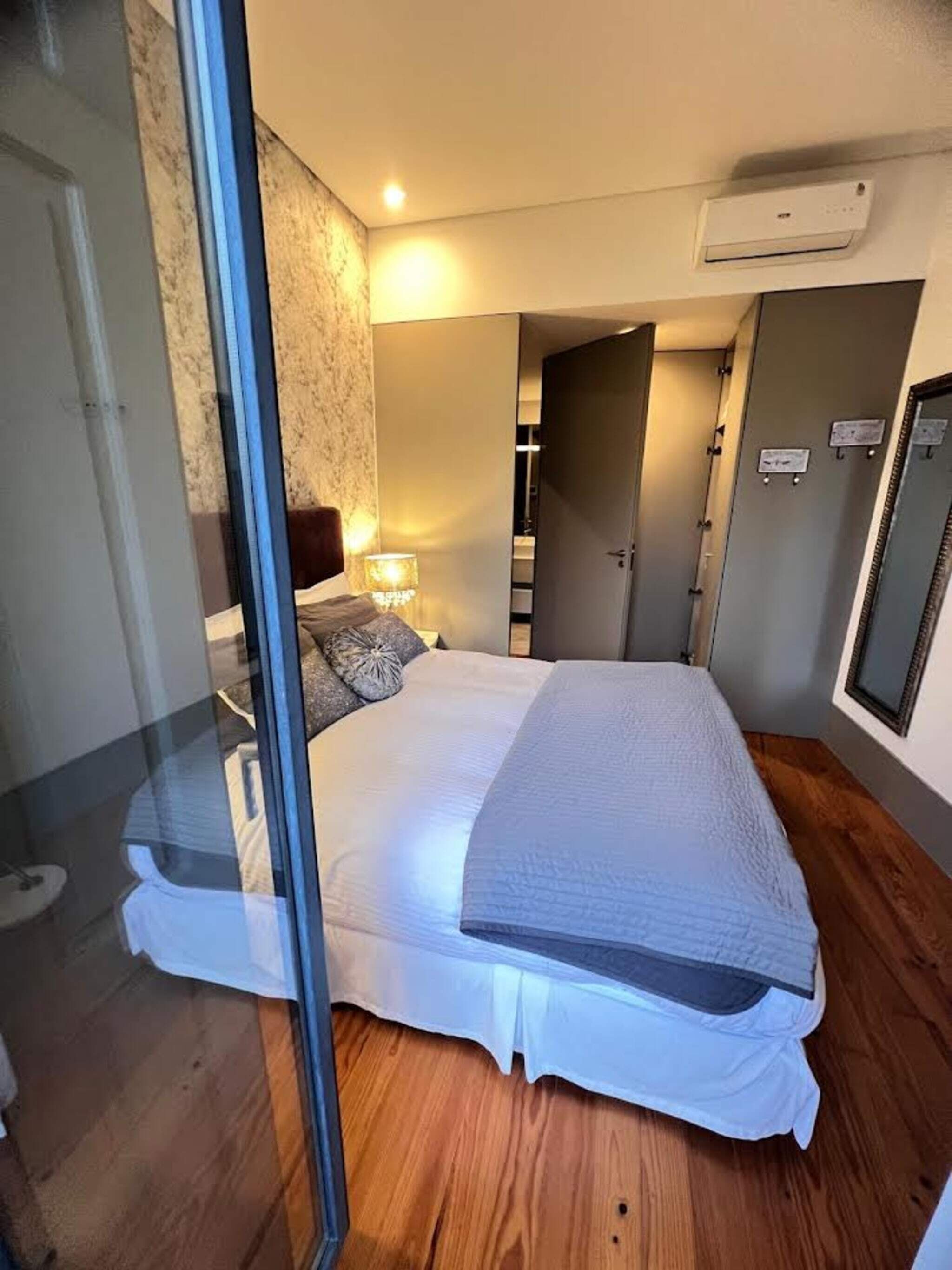 Ein Schlafzimmer mit Bett, Nachttisch, Lampe und Klimaanlage.