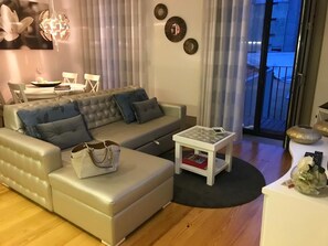 A living room with a sofa, a coffee table, and a dining area with a table and chairs.
