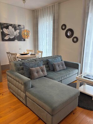 A modern living room with a sectional sofa, a dining table with chairs, and a decorative globe light.