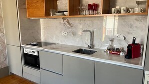 Une cuisine moderne équipée d’un four encastré, d’un évier et d’une machine à café.