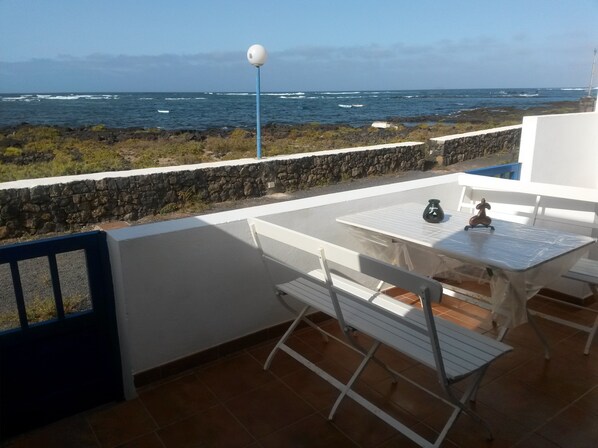 Une terrasse avec une table et des chaises, offrant une vue sur une côte rocheuse et la mer.