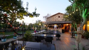 An outdoor dining area with tables and chairs, a pool, and a bar with a sign reading "JOCBAR". - Hotel Yorgo Seferis (Urla)
