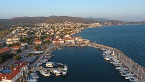 A coastal town with a marina filled with boats, surrounded by residential buildings and hills in the background. - Hotel Yorgo Seferis (Urla)