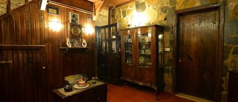 A room with wooden paneling, a stone wall, a wooden cabinet with glass doors, and a tiled floor.