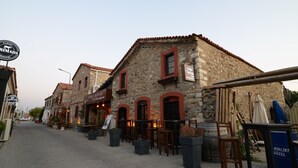 A stone building with a sign for 'Yong Seferis' restaurant, outdoor seating, and a street view. - Hotel Yorgo Seferis (Urla)
