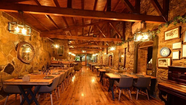 A restaurant with wooden floors and stone walls, featuring tables and chairs set for dining. - Hotel Yorgo Seferis (Urla)