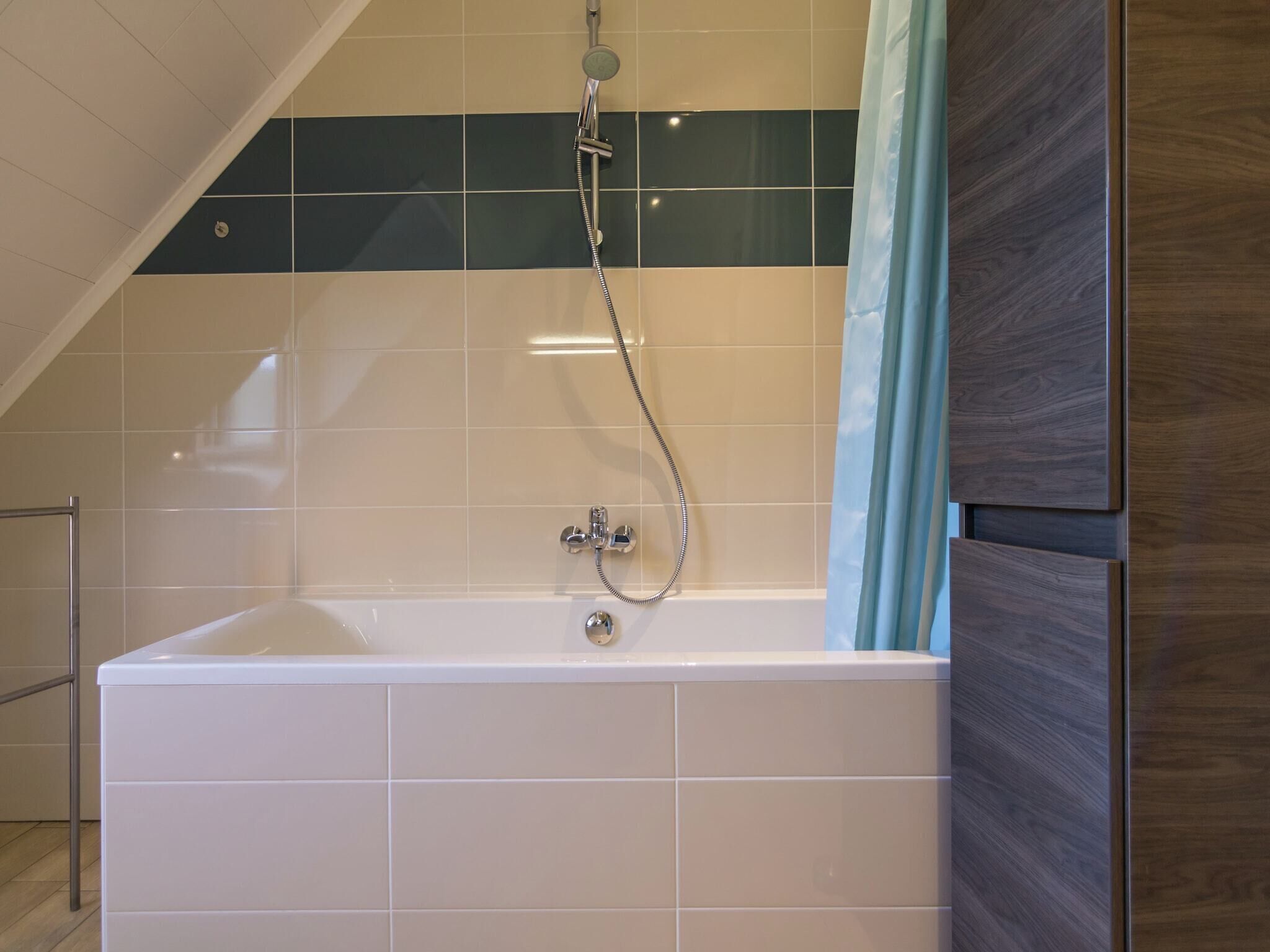 A modern bathroom with a freestanding bathtub, a showerhead, and a towel rack.