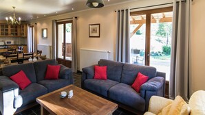 Una sala de estar moderna con dos sofás grises, una mesa de centro de madera y un comedor con mesa y sillas de madera.