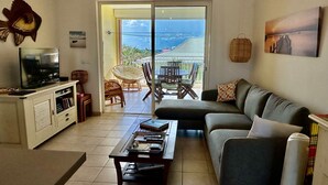 Ein Wohnzimmer mit einer Couch, einem Fernseher und einem Essbereich mit Stühlen und einem Tisch.