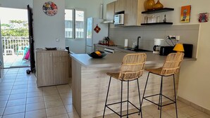 Eine moderne Küche mit Kochinsel, zwei Barhocker und einem Esstisch.