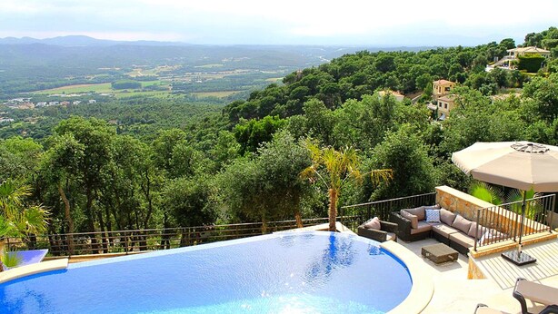 Una piscina con vista a un paisaje exuberante y colinas lejanas.