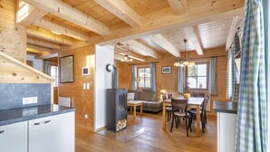 Interno di una baita di legno con angolo cottura, zona pranzo e camino.