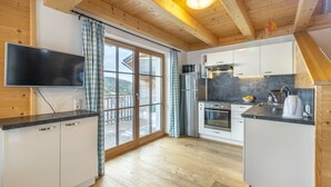 Una cucina moderna con travi in legno, un'ampia finestra e una porta scorrevole in vetro che dà su un patio.