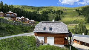 Un rifugio in montagna con chalet in legno, una seggiovia e una vista chiara delle colline circostanti.