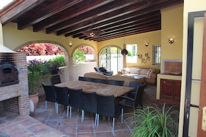 Une terrasse avec un four en briques, du mobilier d’extérieur et des plantes en pot.