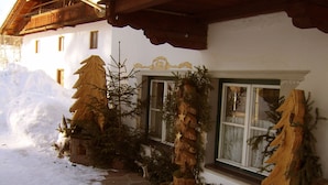 A snow-covered path leading to a building with wooden beams and a white facade.
