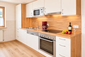 A modern kitchen with white cabinetry, a stainless steel microwave, a coffee maker, and a wine bottle on the counter. - Adlerhof am Sonnenplateau Vacation Rental in Mieming, Pet-Free and Allergy-Friendly (Wildermieming)