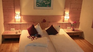 A double bed with two pillows, a bedside table with a lamp, and a framed picture on the wall.