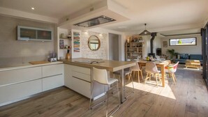 A modern kitchen with a central island, wooden flooring, and a dining area with chairs and a table. - Luxury house with heated Jacuzzi 3km from the center of Vannes  (Ploeren)