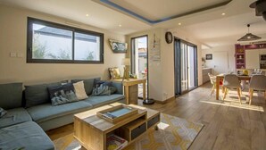A modern living room with a sofa, coffee table, and dining area with chairs. - Luxury house with heated Jacuzzi 3km from the center of Vannes  (Ploeren)