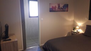 A bedroom with a bed, a nightstand with a lamp, a painting on the wall, and a door leading to another room. - Luxury house with heated Jacuzzi 3km from the center of Vannes  (Ploeren)