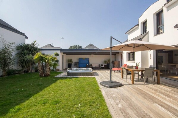 A backyard with a hot tub, outdoor seating, and a wooden deck.