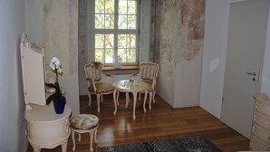 Une pièce avec un plancher en bois, une table à manger avec des chaises, une fenêtre donnant sur des arbres et une porte.