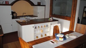 Une cuisine avec un plan de travail en bois, des armoires blanches et une fenêtre dotée d’un cadre en bois.