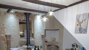 Una llarga taula comuna per a dinar amb un mantell estampat, tamborets i un pilar central.