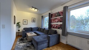 A modern living room with a sectional sofa, a coffee table, and a large window with curtains.