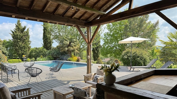 Une terrasse en bois avec une piscine, des chaises longues et une table.