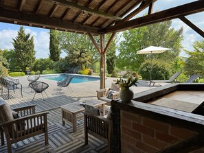 Une terrasse en bois avec une piscine, des chaises longues et une table.