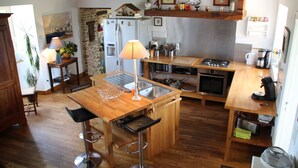 Une cuisine dotée de plans de travail en bois, d’un îlot central avec des tabourets, d’une cuisinière et d’un réfrigérateur.