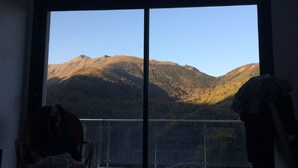 A room with a large sliding glass door leading to a balcony with a mountain view. - Modern and comfortable chalet with stunning views of the Ariege Pyrenees (Gestiès)
