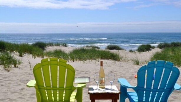 To strandstole med udsigt til havet, med en flaske og glas på et lille bord.