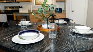 A round dining table with white plates, a glass of water, and a candle holder with a plant. - Team or Family Stay/Peloton/1.9 mile to Grand Park (Westfield)