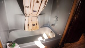 Eine Badewanne mit Holzvorhang, Handtuch und Seifenstück.