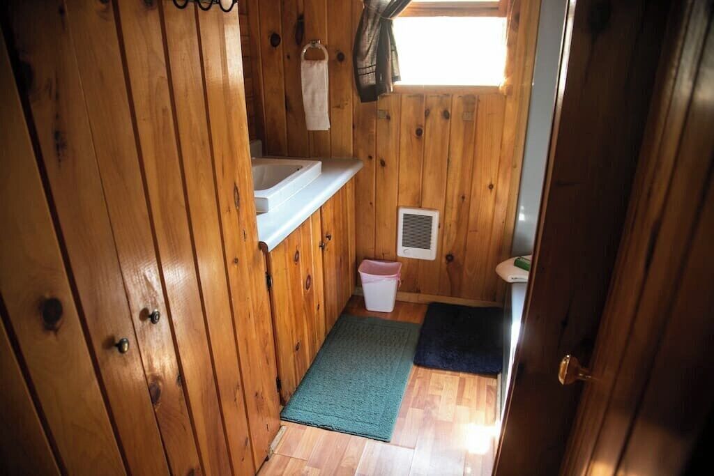 A wooden interior with a bathroom, a small window, and a door.