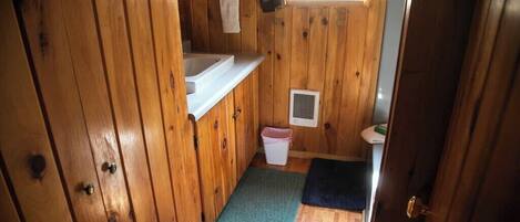 A wooden interior with a bathroom, a small window, and a door.