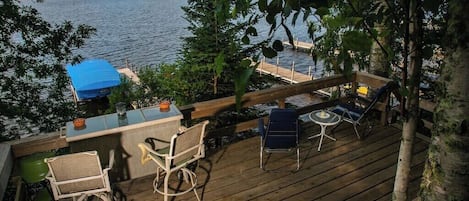 A wooden deck with outdoor furniture, a bar area, and a view of a lake.