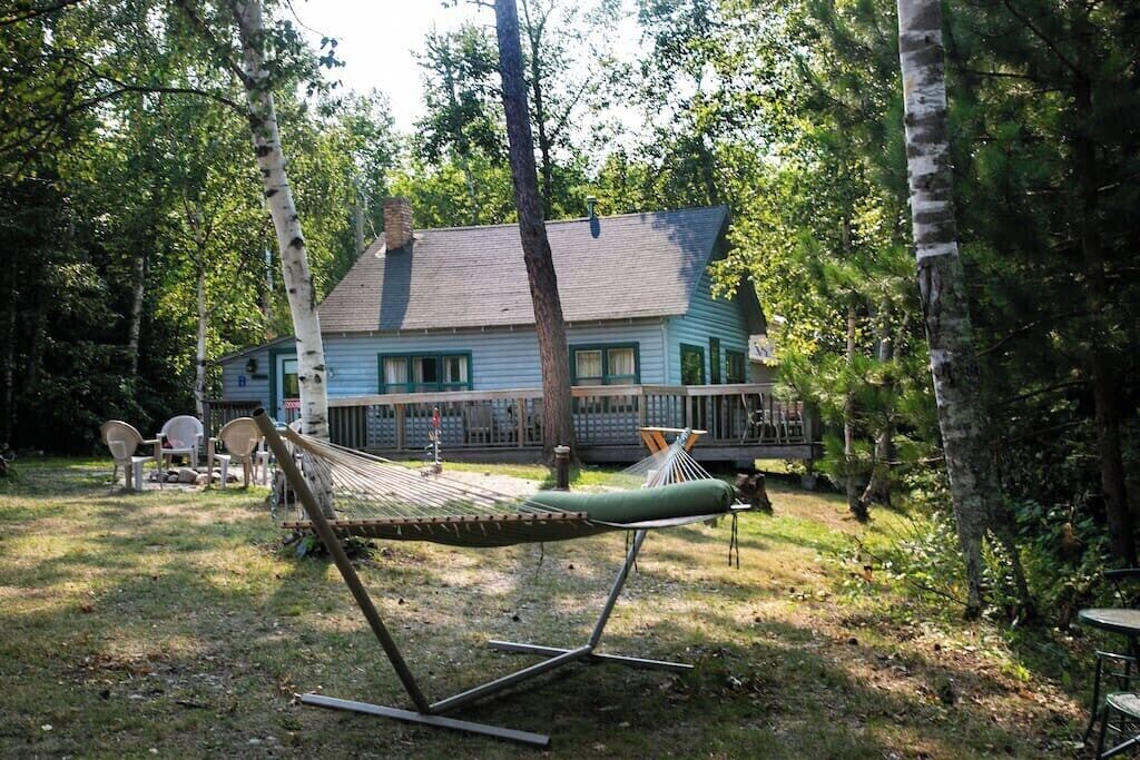 Uma rede em um quintal com uma casa ao fundo.