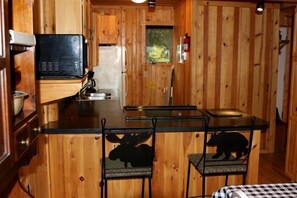 A compact kitchen with wooden walls, a microwave, a refrigerator, and a small window. - Lake Vermilion Getaway Property Great Location, Space, Beach (Tower)