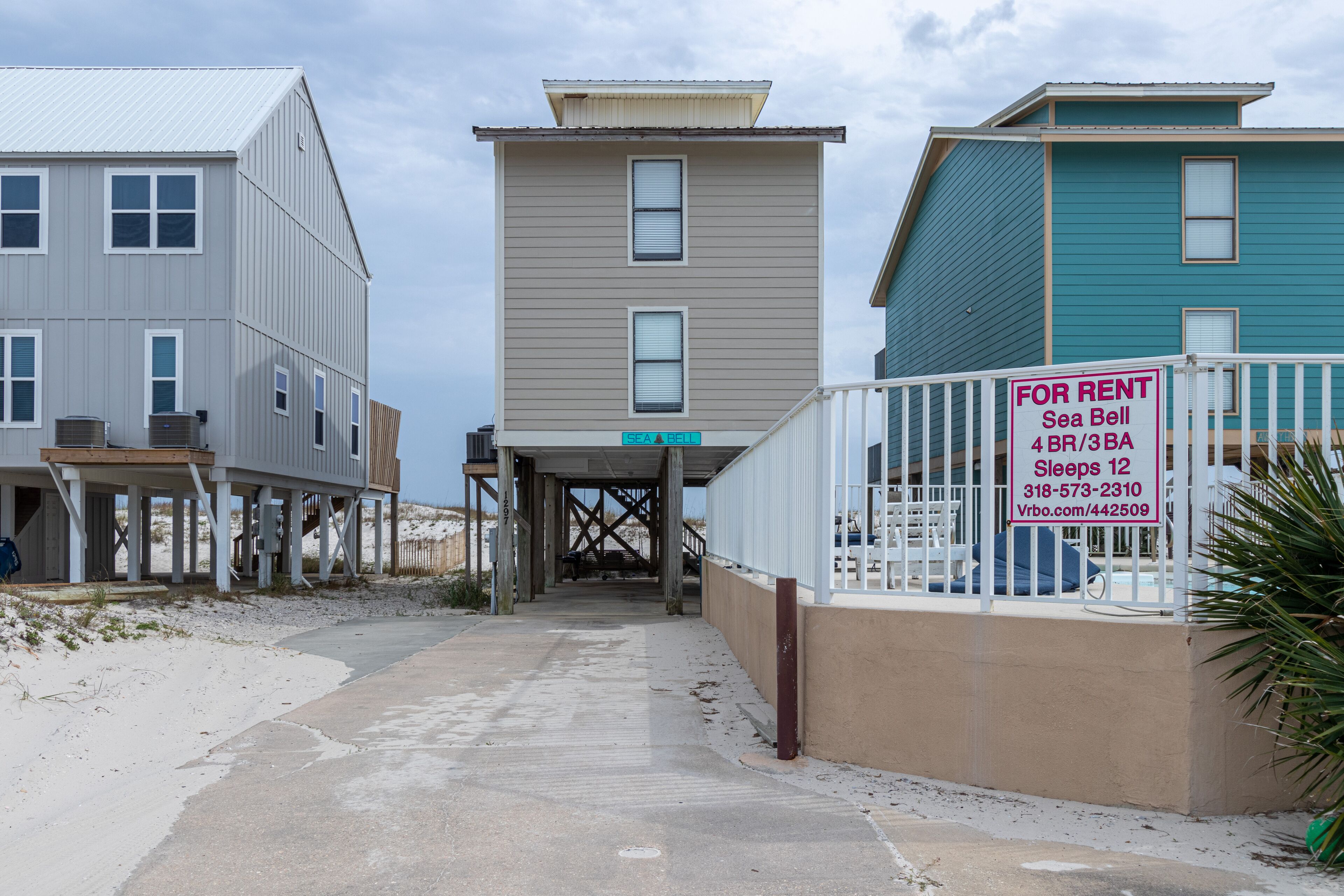 Una propiedad frente a la playa con un paseo techado que lleva a un edificio identificado como "SEA BELL".
