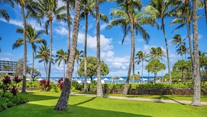 Een tropisch resort met palmbomen, een verzorgd gazon en uitzicht op de oceaan.
