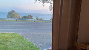 A room with a window overlooking a road and a grassy area.