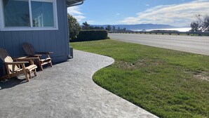 A house with a covered patio, outdoor seating, and a view of a road and distant mountains.