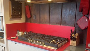 A kitchen with a gas stove, cabinets, and a red countertop.