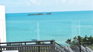 A balcony with a clear view of turquoise ocean waters and two small islands in the distance.