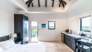 A modern bedroom with a large bed, a desk, and a view of the outdoors.